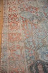 Worn texture of a Bakhtiari rug's red cartouche border and dusty denim blue patterned field.