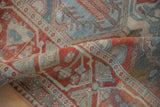 Soft fold on a distressed Bakhtiari rug highlights its textured weave in red and blue.