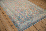 Angled view of a vintage Serbend rug's allover boteh pattern in faded sapphire blue and terracotta.