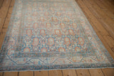 Distressed vintage Serbend rug with terracotta boteh designs, viewed from an angle.