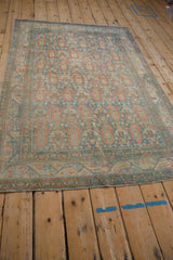 Low angle view of a vintage Serbend rug showing distressed terracotta and blue boteh motifs.