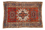 Antique Karaja rug with a large ivory starburst medallion, madder red field, and geometric sky blue borders.