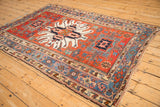 An antique Karaja rug from a side angle, showcasing its bold starburst medallion on a madder red field.
