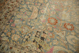 Worn field of a vintage Meshed rug with dusty blue, copper, and pink floral motifs.