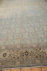 Angled view of a distressed Tabriz carpet's low pile, showing Herati and turtle samovar motifs.