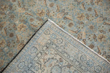 Folded corner of a distressed Tabriz carpet reveals its hand-knotted foundation and low-pile texture.