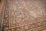 Distressed Mahal carpet corner showing softened rose, blue floral field and intricate geometric borders.