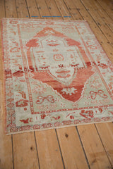Angled view of a vintage distressed Oushak showing the geometric border and worn, low pile.