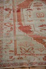 Angled view of a distressed Oushak rug showing even wear across the hand-knotted pile and red motifs.