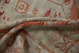 A close-up fold shows the distressed cherry red patterns and low, even pile of the vintage Oushak rug.