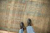 Distressed vintage Belouch carpet with a low pile showing rectangular and pawn motifs in blue, brown, and beige.