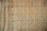 Close-up of a vintage Belouch border with geometric pawn motifs in dusty blue, brown, and sand.