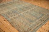 Angled view showing the geometric pattern and heavy abrashes of the distressed Belouch carpet.