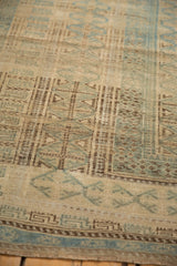 Detail of the distressed carpet's low pile showing the geometric pawn design in brown and pale blue.