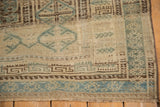 Pawn design motifs in dusty blue and brown on the low-pile border of a vintage Belouch carpet.