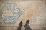 A look down at the soft, time-softened texture of a Caucasian rug with blue and beige medallions.