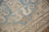 Worn texture of a Caucasian rug with sky blue and beige cloud-band and snowflake motifs.