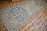 Distressed Caucasian runner with large sky blue medallions and geometric borders viewed at an angle.