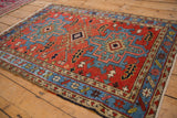 Angled view of a vintage Persian Karaja rug's geometric medallions on a madder red field.
