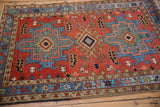 Vintage Persian Karaja rug with geometric medallions in sky blue on a brick red field.