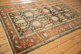 Angled view of a vintage Mehriban rug highlighting its charcoal lattice field and rich rust borders.