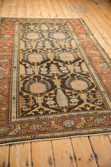 Angled perspective of a vintage Persian Mehriban rug, showing its charcoal field, rust border, and geometric lattice pattern.