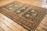 Angled view of a vintage Mehriban rug, displaying its geometric cypress tree pattern and rust border.