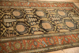 Charcoal geometric field and rich rust floral border of a hand-knotted vintage Persian rug.