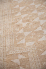 Distressed Belouch rug detail: geometric pinwheel patterns, tiered blossom border, neutral hues.