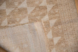 Two-tone beige geometric pinwheels on distressed Belouch rug, showing tight hand-knotted foundation.
