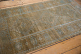 Angled view of the decorative wear and powder blue patterns on a vintage Belouch rug.