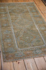 Side angle of a distressed Belouch rug displaying its time-softened powder blue and brown pile.