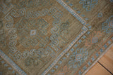 Low pile of a distressed Belouch rug showing blue pawn motifs and abrashed coffee brown tones.