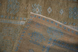 Folded corner of a distressed Belouch rug showing the woven back and textured, low pile.