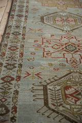 Angled view of a vintage Karaja runner's boteh border and distressed, low-pile weave.