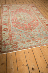 Angled perspective of a distressed Malayer rug with time-softened raspberry red and powder blue tones.