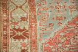 Detail of a vintage Malayer rug's raspberry red border and dusty blue Herati field.
