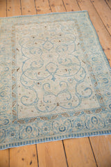Powder blue scrolling arabesques and germinating border on the distressed antique ivory Tabriz rug.