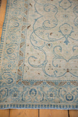 Powder blue arabesque vines on antique ivory distressed Tabriz rug, with patterned borders.
