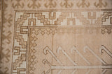 Reciprocating pawn design border in camel and ivory on a distressed vintage Kars carpet.