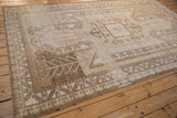 Angled view of a vintage Kars carpet highlighting the large shield medallion and abrashed sand and camel tones.