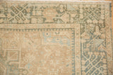 Corner detail of a distressed Karaja rug showing the low pile and geometric borders in sand and dusty teal.
