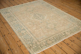 Distressed vintage Karaja rug viewed at an angle, showing the low-pile texture and dusty teal borders.
