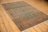 Angled view of a vintage Malayer rug showing color abrashes across its dusty blue and rust design.