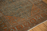 Angled view of a distressed Malayer rug's rust border with stylized Herati Samovar motifs.