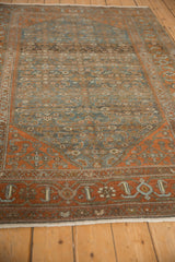 Perspective view of a distressed Malayer rug highlighting the textural, worn pile and terracotta and dusty blue palette.