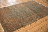 Angled perspective of a distressed Malayer rug highlighting its Herati pattern in dusty blue and terracotta.