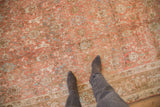 A view looking down at the time-softened texture of a distressed vintage Bijar carpet in blush and slate blue.