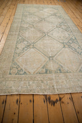 Distressed Hamadan runner corner, displaying faded diamond lattice and a subtle striped border.