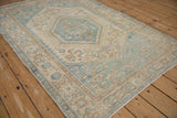 Angled view of a distressed Hamadan rug highlighting its serrated medallion and low pile.